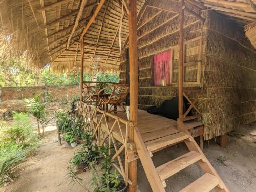 a room in a thatched hut with a bench and a chair at Jungle House Kep in Kep