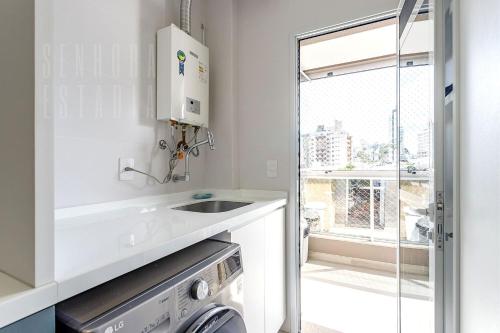 uma cozinha com um lavatório e uma máquina de lavar roupa em Requinte Floripa - Apartamento - Design Moderno em Florianópolis