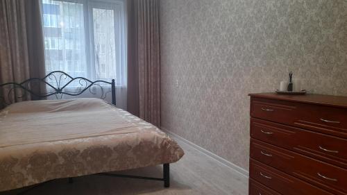 - une chambre avec un lit, une commode et une fenêtre dans l'établissement Жемчужина, à Uralsk
