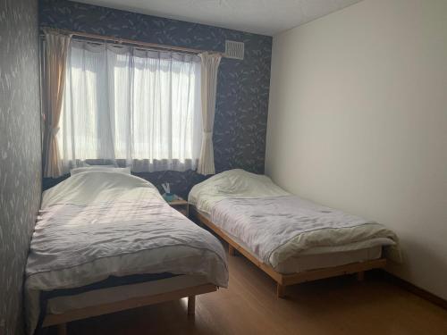 two twin beds in a room with a window at STAY Sakura in Bibai