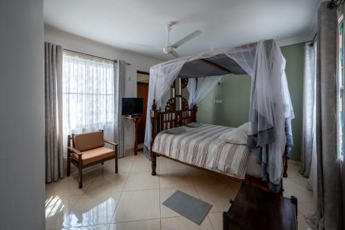 1 dormitorio con cama con dosel y silla en Nyali Villa, en Mombasa