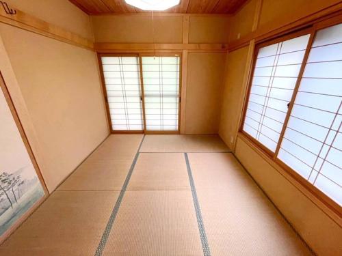 an empty room with three windows in a room at 飯能テラス in Hanno