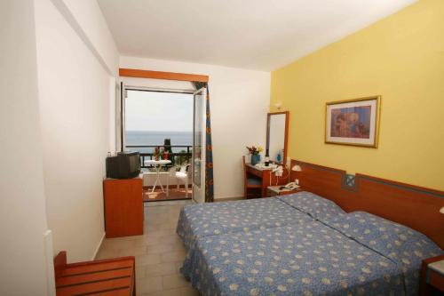 a bedroom with a bed and a view of the ocean at Hotel Glicorisa Beach in Pythagoreio
