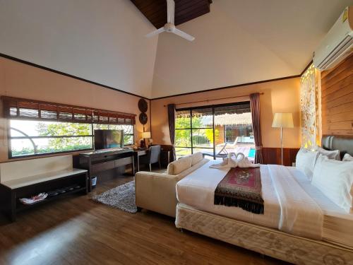 ein großes Schlafzimmer mit einem großen Bett und einem Sofa in der Unterkunft Naga Tara Boutique Resort in Phayao