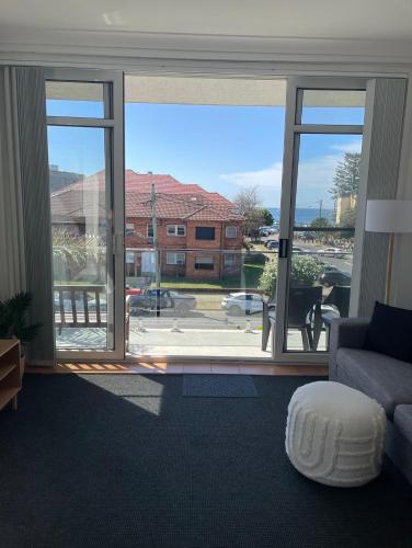 a living room with a large window and a couch at Eloura Gardens 100m to Beach in Cronulla
