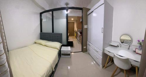 Cozy 1Br with Netflix & Balcony Pool View Condo في مانيلا: غرفة نوم صغيرة بها سرير ومغسلة
