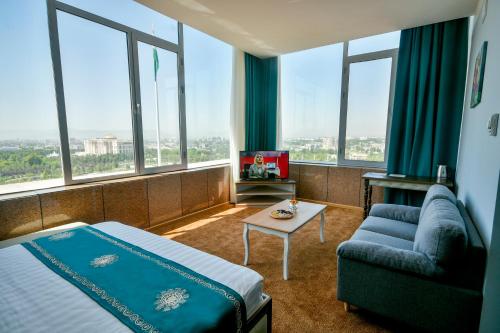 a hotel room with a bed and a couch and windows at Hotel Shumon in Dushanbe