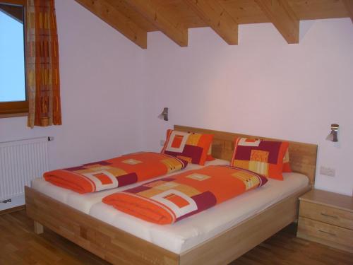 ニーダートハイにあるHaus Neurauterのベッドルーム1室(オレンジとオレンジの枕が備わるベッド2台付)