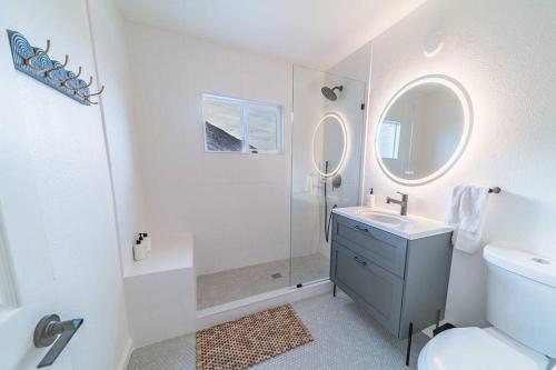 a white bathroom with a sink and a mirror at By Park Entrance, Hot Tub, Stars, Private ܍ WKNDR in Twentynine Palms