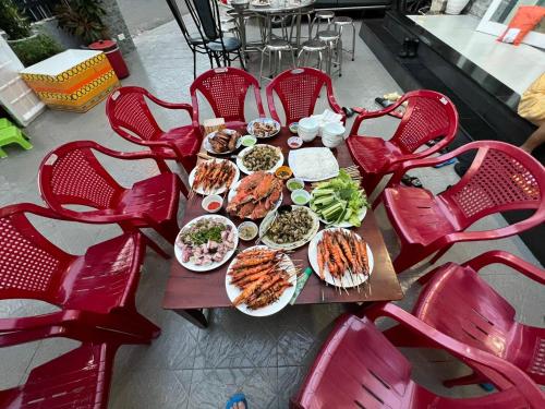 Nguyễn Kim Motel في لونغ هاي: طاولة عليها أطباق من الطعام وكراسي حمراء