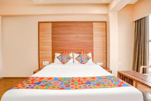 a bedroom with a large bed with a wooden headboard at FabHotel Mahadev Residency in Kolshet