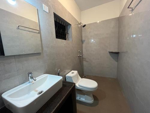 a bathroom with a white sink and a toilet at Morjim Sunset Guesthouse- Apartments with Kitchen & AC Rooms in Morjim