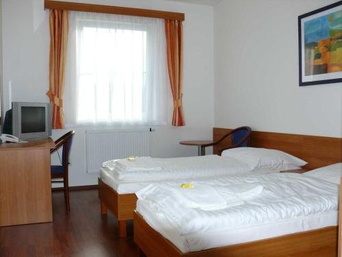 a bedroom with two beds and a desk and a television at Hasičský hotel Přibyslav in Přibyslav