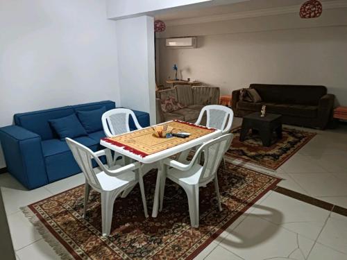 een tafel en stoelen in een woonkamer met een blauwe bank bij Mohamed Afifi Florence El Montazah - 2 Bed rooms - "Compound" in Alexandrië