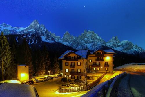 a building with snow covered mountains in the background at GH Hotel Fratazza in San Martino di Castrozza