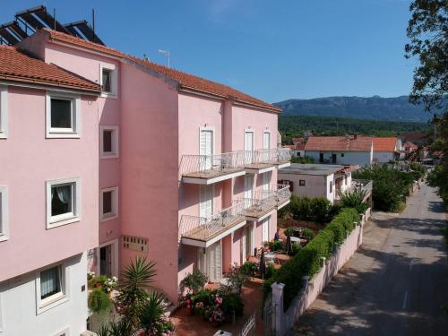 Une rangée de bâtiments roses dans une rue dans l'établissement Apartments Josi - 200 m from sea, à Vrboska