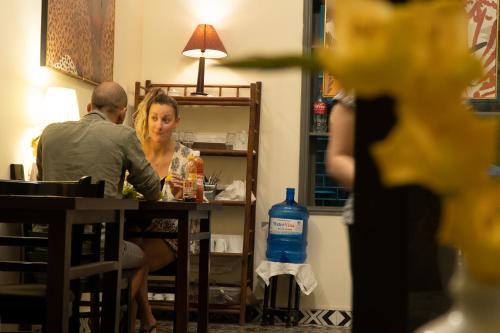 Ein Mann und eine Frau sitzen an einem Tisch in der Unterkunft Perfume's Cozy House in Hanoi