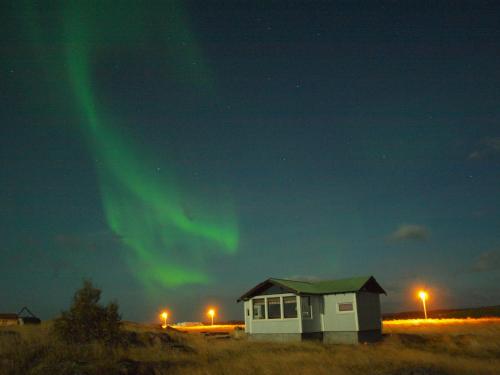 a house with the aurora dancing in the sky at Hömluholt Holiday Homes in Hömluholt