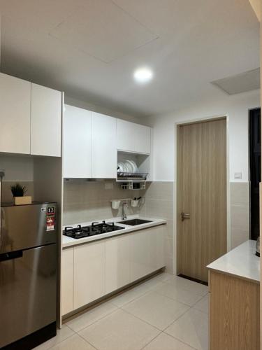 a kitchen with white cabinets and a stainless steel refrigerator at KLCC Kampung Baru Cottage - Homestay in Kuala Lumpur