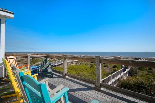 a deck with chairs and the ocean in the background at Turtle Watch Too by Oak Island Accommodations in Caswell Beach