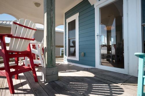 a red rocking chair sitting on the porch of a house at Turtle Watch Too by Oak Island Accommodations in Caswell Beach