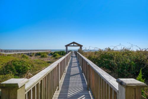 a wooden boardwalk leading to a bridge over the beach at Turtle Watch Too by Oak Island Accommodations in Caswell Beach