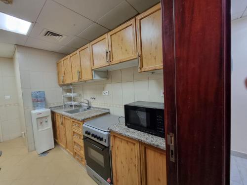 a kitchen with wooden cabinets and a black microwave at MBZ - Cosy Separate Room in Unique Flat in Abu Dhabi