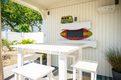 a table and chairs on a patio with a surfboard at The Anchor Holds by Oak Island Accommodations in Oak Island