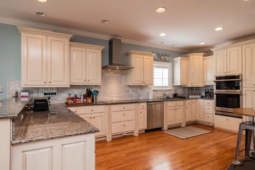 a large kitchen with white cabinets and wooden floors at The Anchor Holds by Oak Island Accommodations in Oak Island