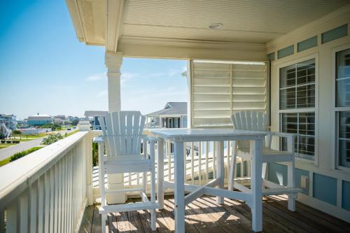 two chairs and a table on the porch of a house at The Anchor Holds by Oak Island Accommodations in Oak Island