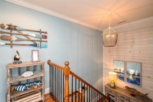 a hallway with a wooden staircase with a chandelier at The Anchor Holds by Oak Island Accommodations in Oak Island