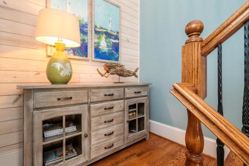 a lamp on top of a dresser next to a staircase at The Anchor Holds by Oak Island Accommodations in Oak Island