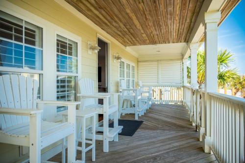 a porch with white chairs and a wooden ceiling at The Anchor Holds by Oak Island Accommodations in Oak Island