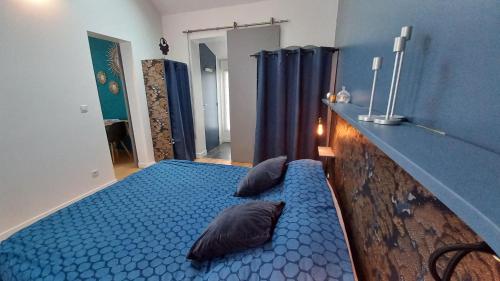 a bedroom with a blue bed with two pillows on it at Les Appartements du 104 in Saint-Jean-de-Monts