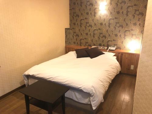 a bedroom with a bed with white sheets and black pillows at 尾道ラブラス in Onomichi