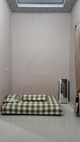 HomeStay Pandan Baru في Halangan: سرير في غرفة بيضاء مع مرتبة منقوشة