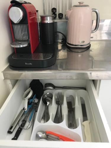 a drawer in a refrigerator filled with utensils at Tui Cottage in Te Arai