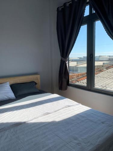a bedroom with a bed and a window with a view at Nomad Stay in Phan Rang