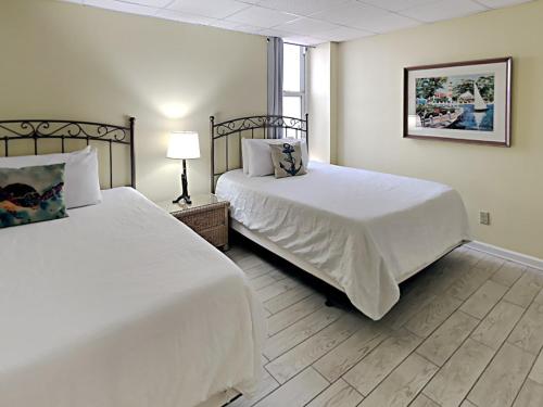 a bedroom with two beds and a lamp at Carefree 108 in Pensacola Beach