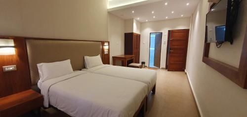 een hotelkamer met een bed en een televisie bij The Nisha Continental in Kottayam