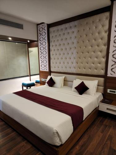 a bedroom with a large bed with a large headboard at Hotel Preethi International in Mysore