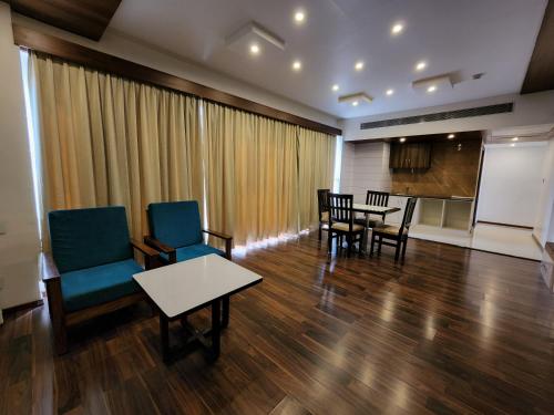 a living room with chairs and a table and a kitchen at Hotel Preethi International in Mysore