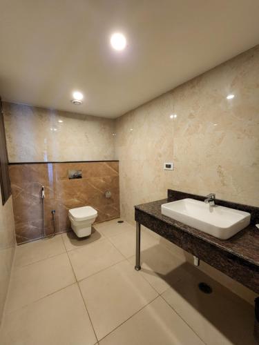 a bathroom with a sink and a toilet at Hotel Preethi International in Mysore