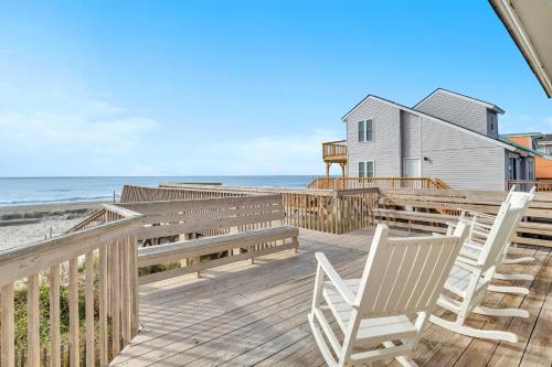 a deck with chairs and a house and the ocean at Wahoo by Oak Island Accommodations in Oak Island