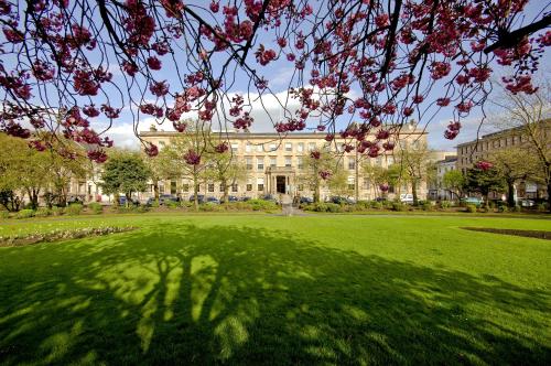 a large building with a green lawn with a tree at Kimpton - Blythswood Square Hotel, an IHG Hotel in Glasgow