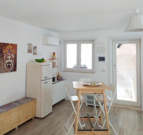 a small kitchen with a table and a refrigerator at A Casuzza di Mazzeo in Mazzeo