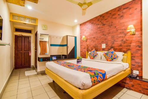 a bedroom with a large bed and a brick wall at FabHotel Kinnera Comforts Railway Station in Visakhapatnam