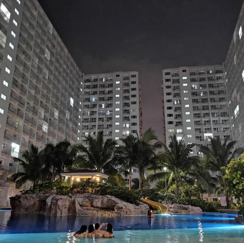 a hotel swimming pool with people in the water at night at SHORE RESIDENCE D13 shortwalk Mall of asia near airport in Manila