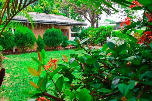 a garden with green grass and red flowers and a house at Beach Walk Villa in Trincomalee