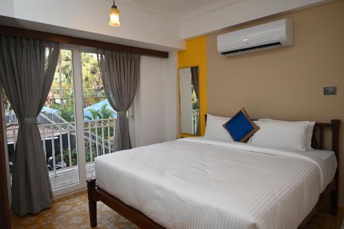1 dormitorio con 1 cama y balcón en Richmonde Ananta Elite Luxurious Villa & Apartments,Goa en Baga